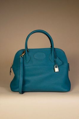 blue leather handbag with a padlock on top of it