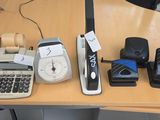 several cell phones and a calculator sit on a desk