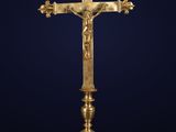 a gold cross on a stand with a crown on top