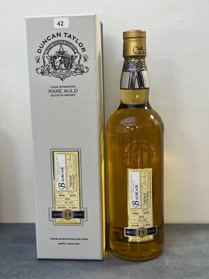 La bouteille de whisky se trouve à côté de la boîte, sur la table.