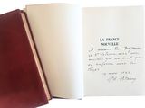 un livre ouvert, sur lequel est posée une note manuscrite, posé sur une table