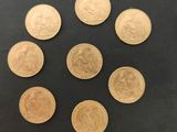 six pièces d'or sont disposées en cercle sur une surface noire
