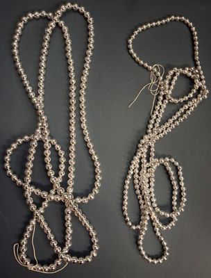 deux colliers composés de perles d'argent sur un fond noir