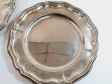 two silver plates sitting on a white table