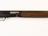 un fusil posé sur une surface blanche, muni d'une crosse en bois
