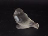 a glass bird that is sitting on a black surface