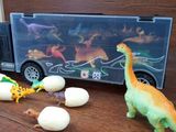 a toy truck with a toy dinosaur and eggs on the table