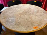 a marble table with four black chairs in front of a red curtain