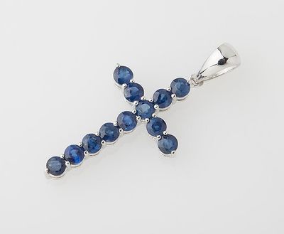 a blue sapphire cross pendant on a white background