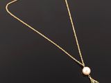 a gold necklace with a pearl and a pendant on it