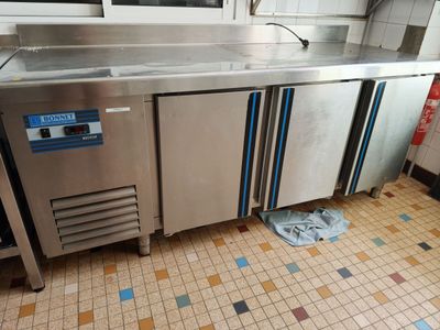 a stainless steel counter in a kitchen with a tiled floor