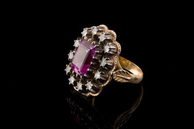 un gros plan d'une bague en pierre rose posée sur une surface noire
