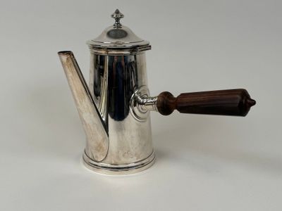 une cafetière en argent avec une poignée en bois sur une surface blanche