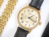 a gold watch and a gold chain on a white surface