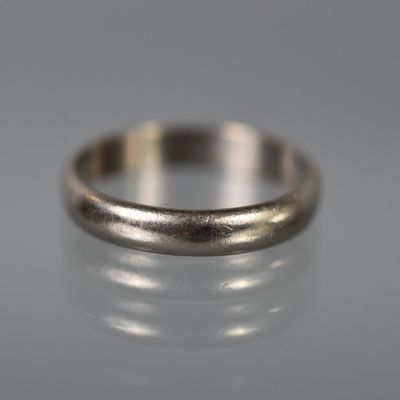 un gros plan d'une bague en argent posée sur une surface réfléchissante