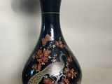 a black vase with a gold trim and a bird on it