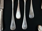 a lot of silver spoons and knives on a black table