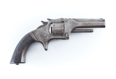 un vieux pistolet est posé sur une surface blanche, devant un fond blanc