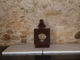 une petite horloge posée sur une table devant un mur de pierre