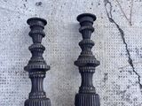 deux bougeoirs noirs posés sur un sol en béton