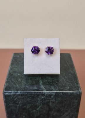 une paire de boucles d'oreilles en améthore posée sur un bloc de marbre