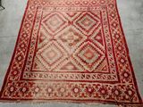un vieux tapis rouge et beige orné d'un motif en losanges