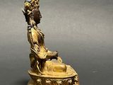 bronze statue of a person sitting on a pedestal with a bowl in his hand