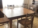 une table et des chaises dans une pièce où est accrochée une horloge au mur
