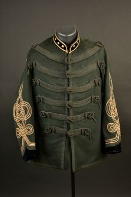 une veste militaire verte ornée de broderies dorées, posée sur un présentoir pour mannequin