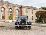 a vintage car parked in front of a large building