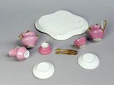 a pink and white tea set on a table