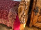 a bed with a red bedspread sitting next to a dresser