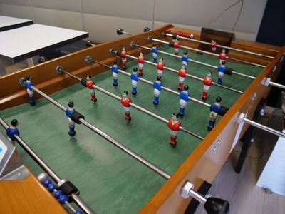 un baby-foot dans une pièce où se trouve un ordinateur portable posé sur la table
