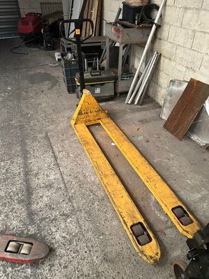 a forklift sitting in a garage next to a pile of wood