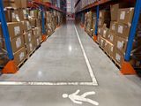 a picture of a warehouse aisle with boxes and a man on the floor