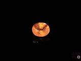 a close up of an orange diamond on a black surface