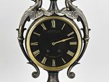 une horloge posée sur un support sur fond blanc