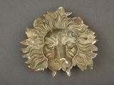 a gold lion head brooch on a gray surface