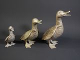 three ducks standing next to each other on a black surface