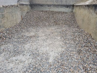 un tas de gravier par terre, à côté d'un mur en béton