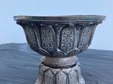 un bol ancien en argent posé sur une table en bois, sur fond blanc