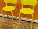 pair of yellow metal stools against an orange wall in a room