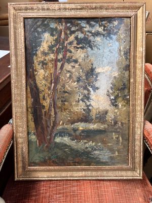 une peinture à l'huile représentant un paysage boisé, encadrée et posée sur une chaise