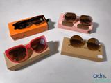 trois paires de lunettes de soleil dans une boîte posée sur une surface blanche