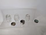 three salt and pepper shakers sitting on a clear shelf