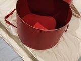 une boîte rouge posée sur un lit, à côté d'un oreiller
