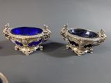 two silver and blue glass vases sitting on top of a table