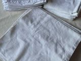 trois serviettes blanches ornées de monogrammes sont posées sur un lit