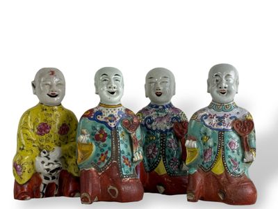 trois figurines représentant des hommes asiatiques sont assises sur une surface blanche