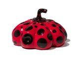 a small red and black pumpkin on a white surface